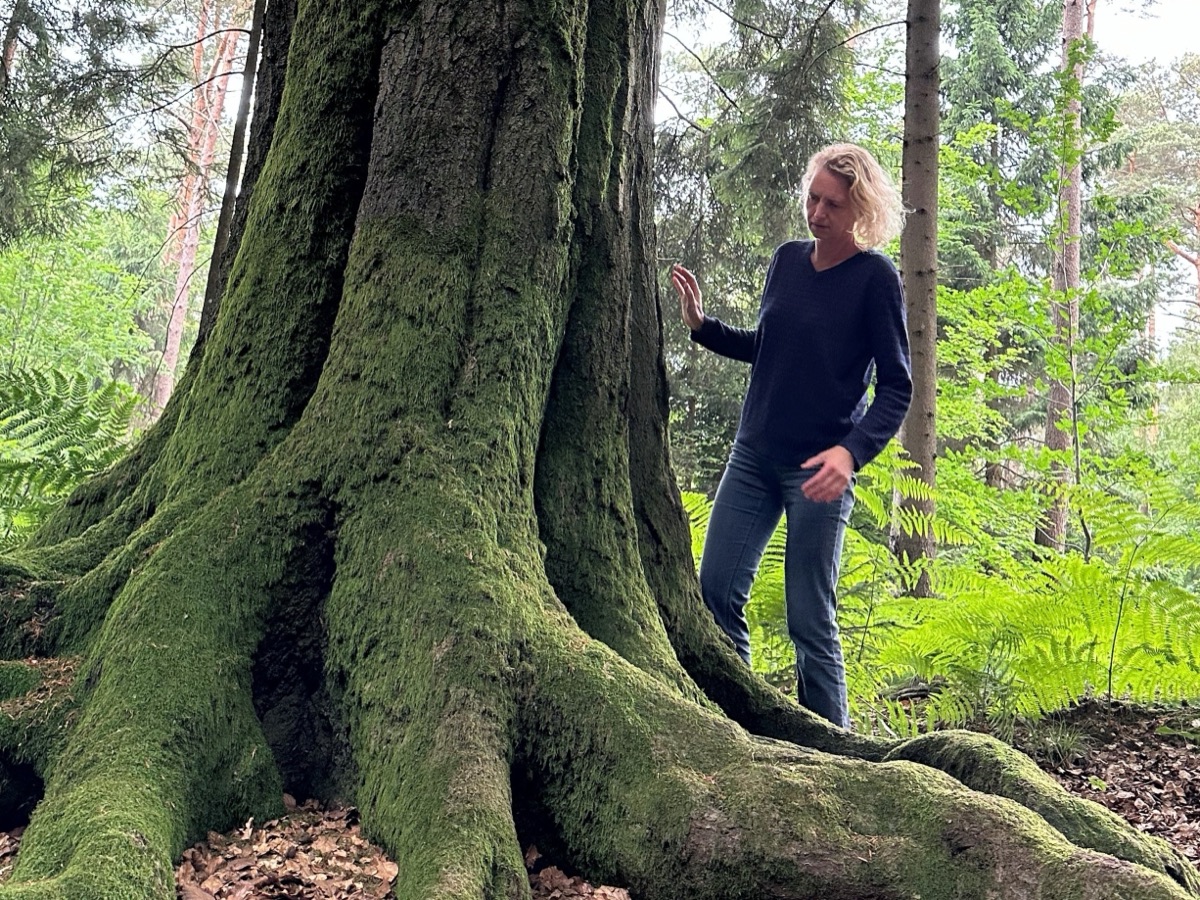 Renske bij de bemoste voet van een grote boom