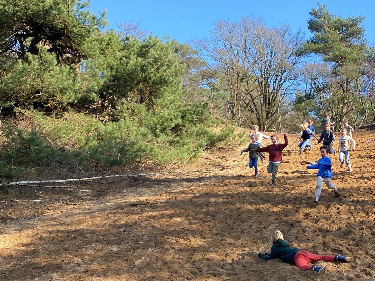Kinderen rennen en spelen op een zanderige heuvel op de hei