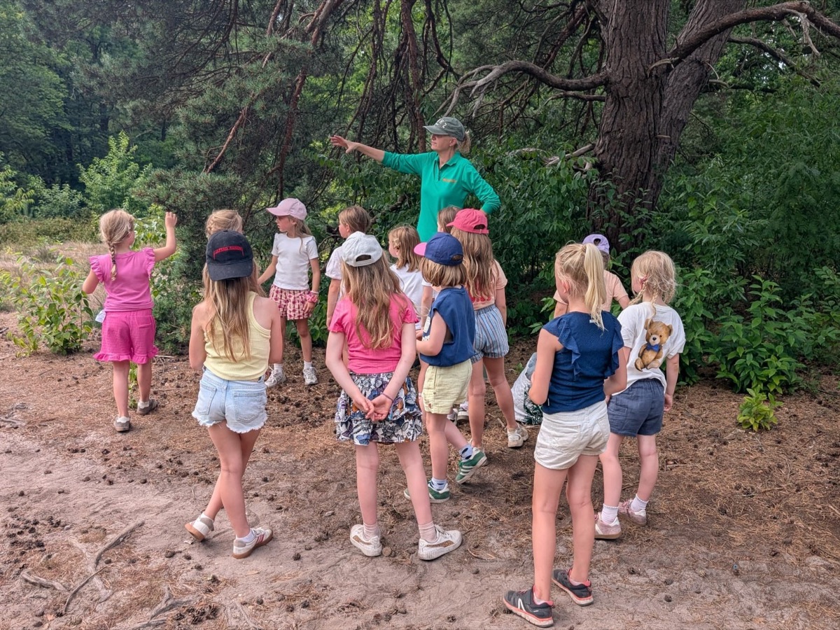Renske wijst een groep kinderen de weg aan de bosrand