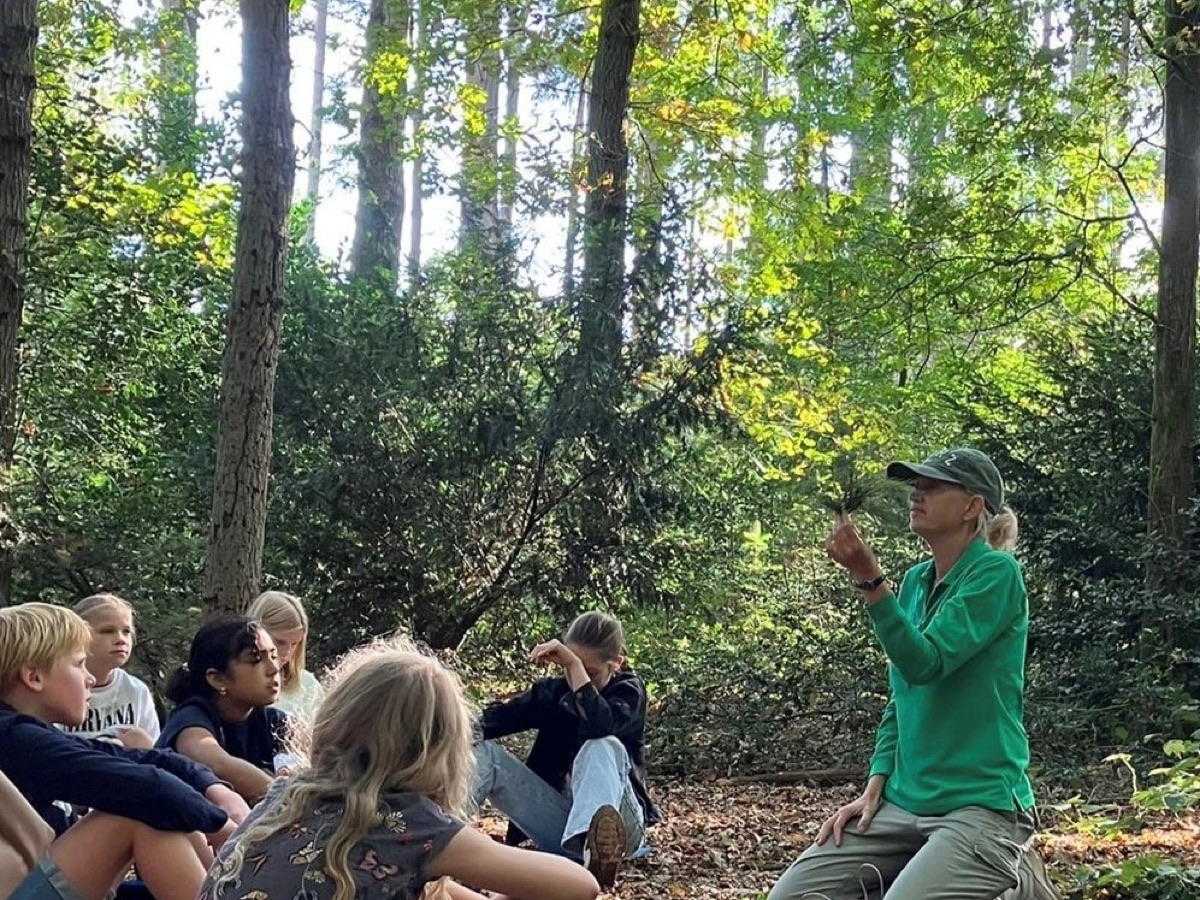 Renske vertelt aan een groep leerlingen in het bos