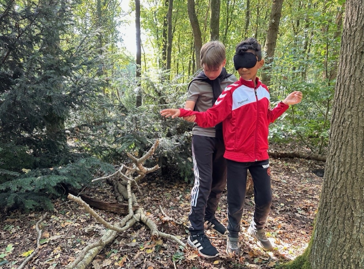Leerling laat een geblinddoekte klasgenoot een boom voelen