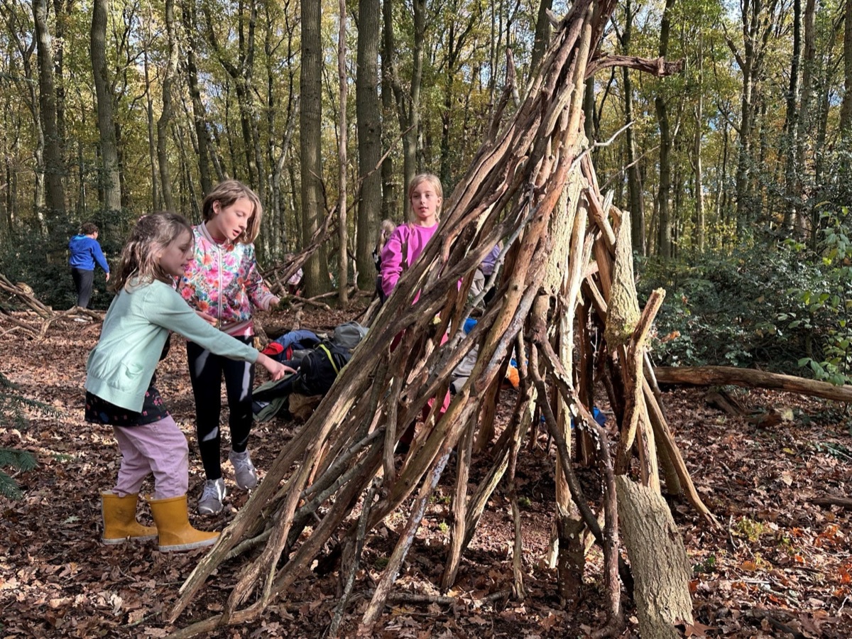 Kinderen bouwen samen een hut van takken in het bos