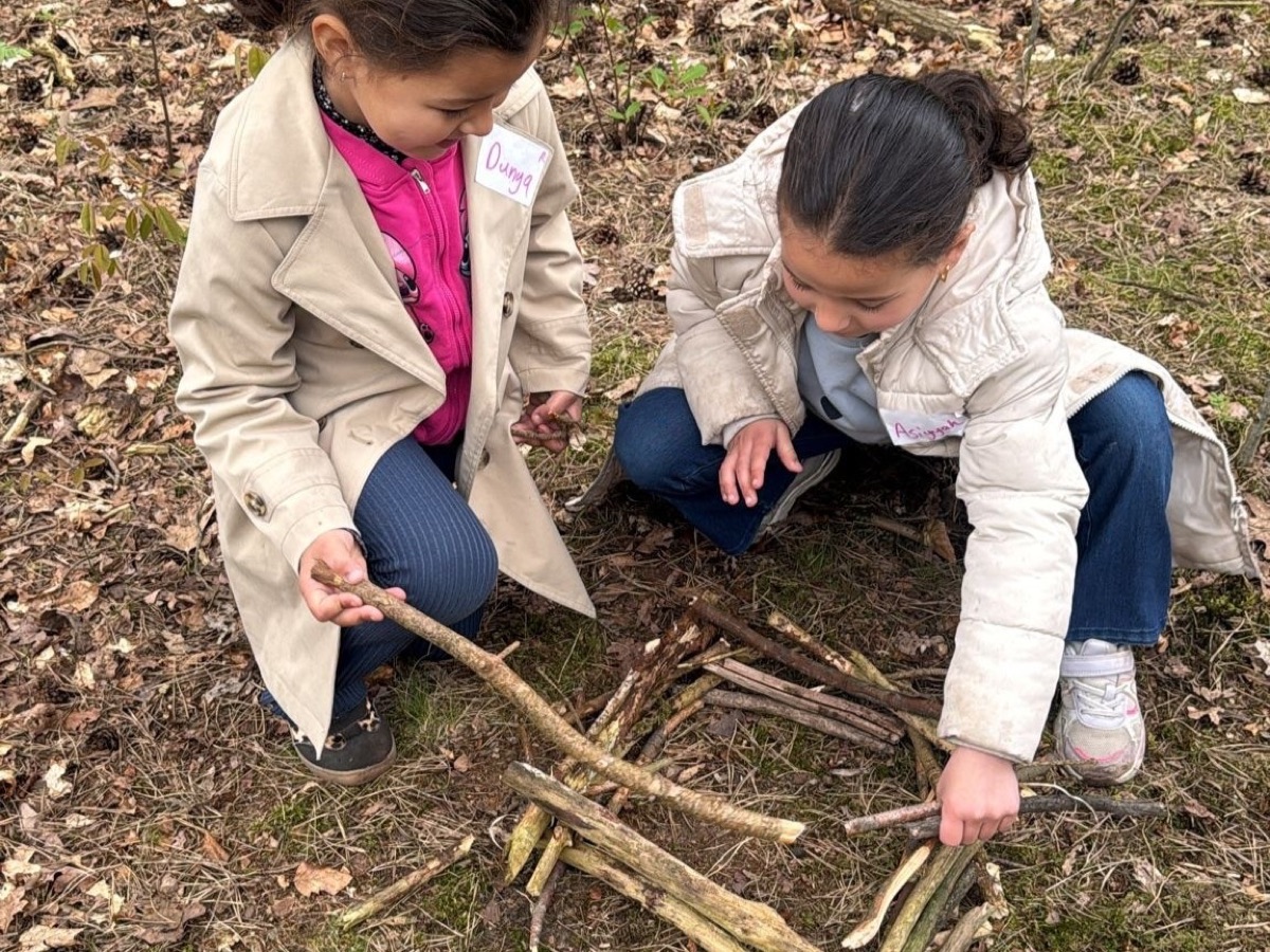 Twee meisjes bouwen met takken in het bos